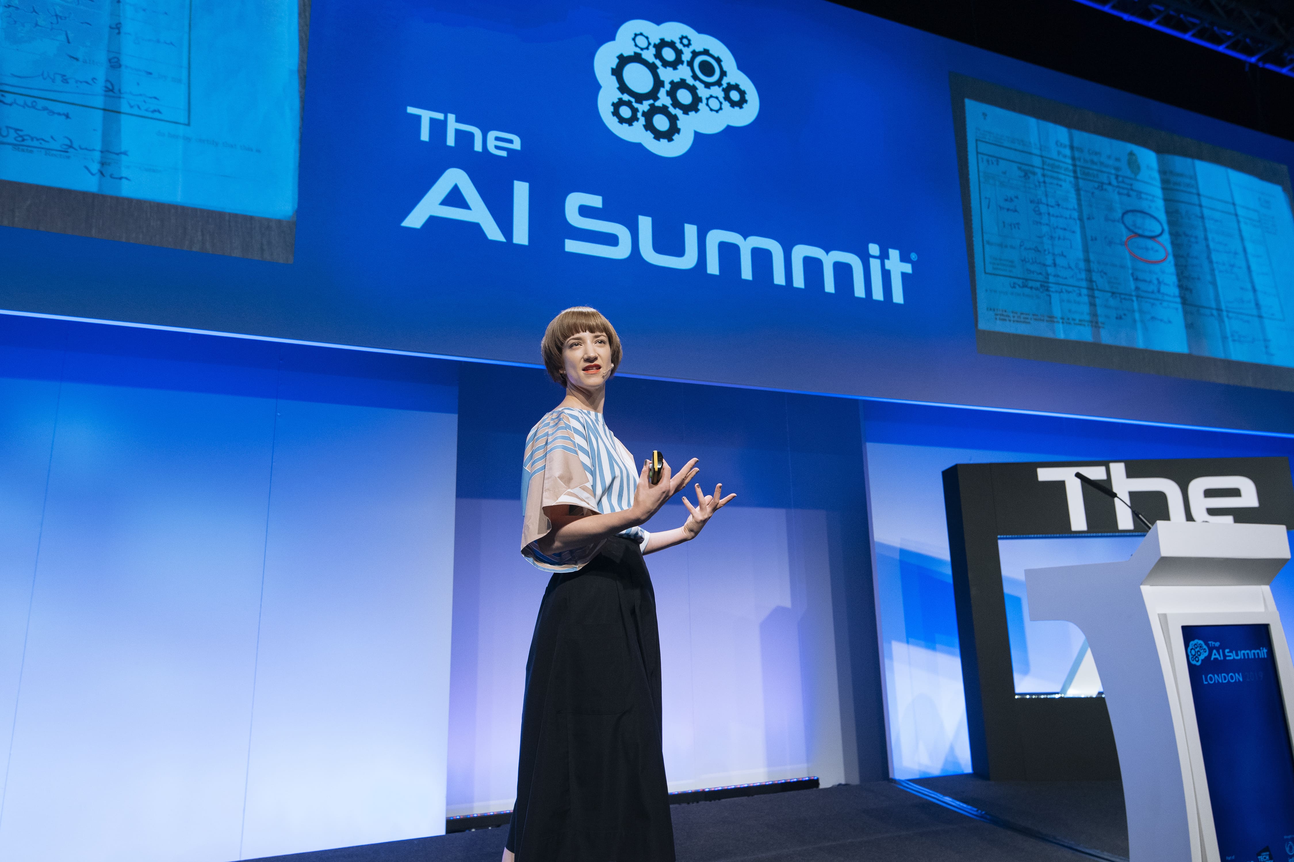 Speaker presenting at The AI Summit London, discussing advancements in artificial intelligence with visuals displayed on screen
