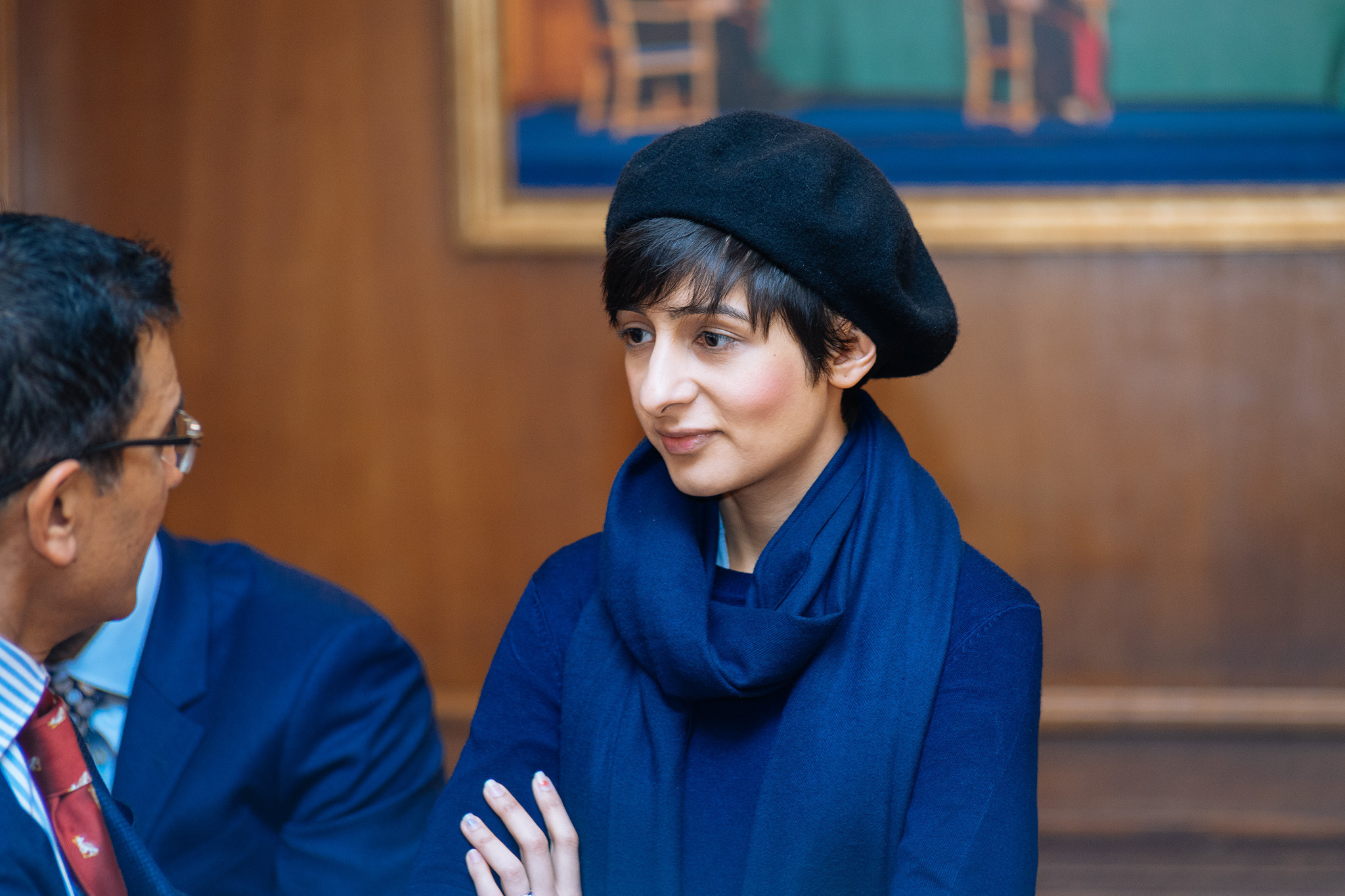 A woman wearing a black hat and a blue scarf.