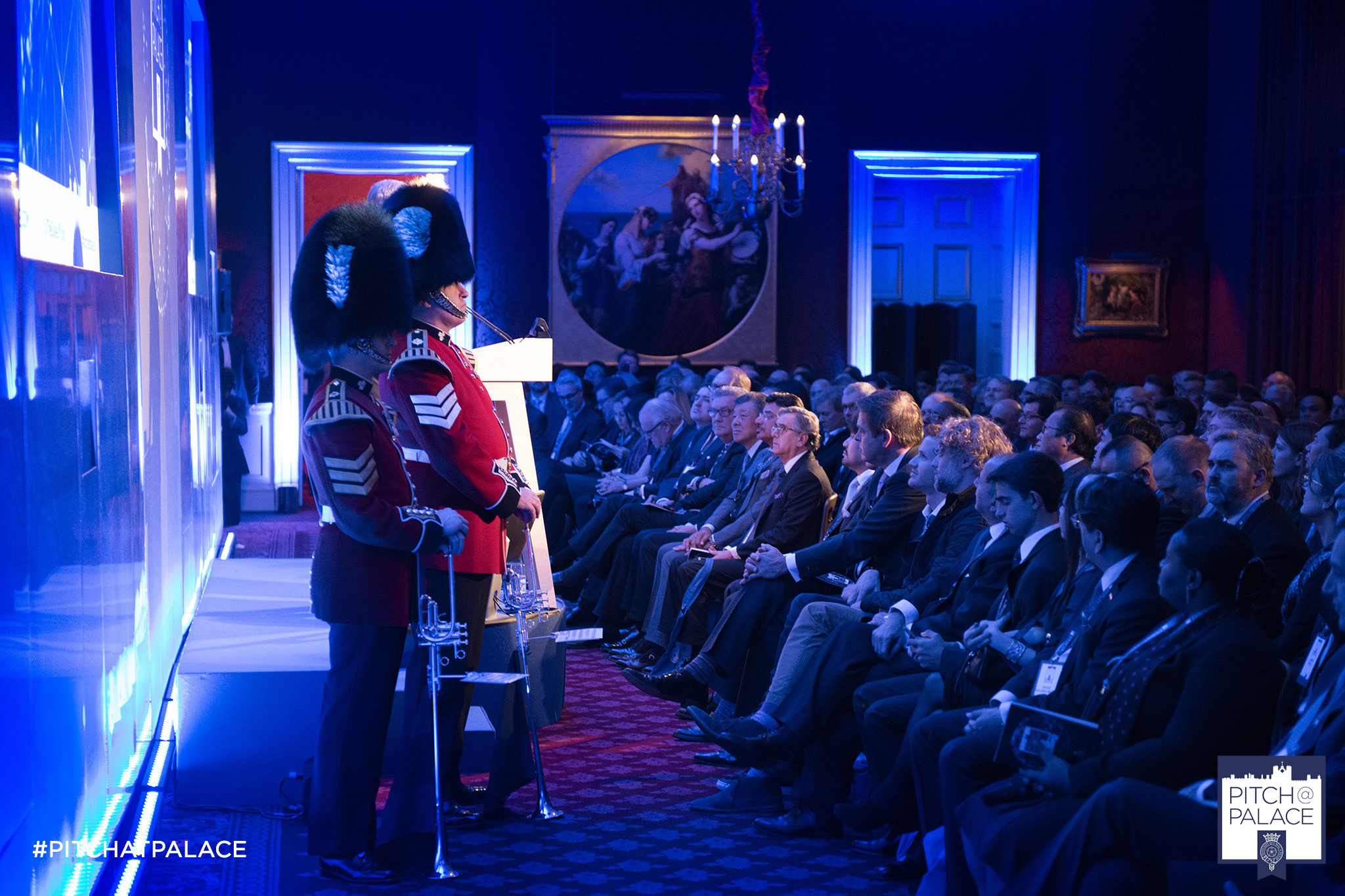 A man in a red jacket stands in front of a crowd.