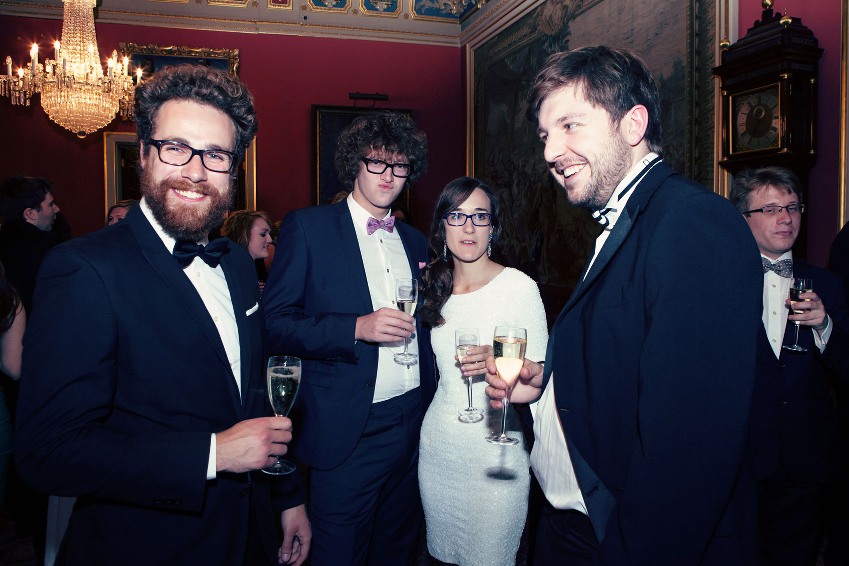 A group of people in a room with a man wearing a black suit and glasses.
