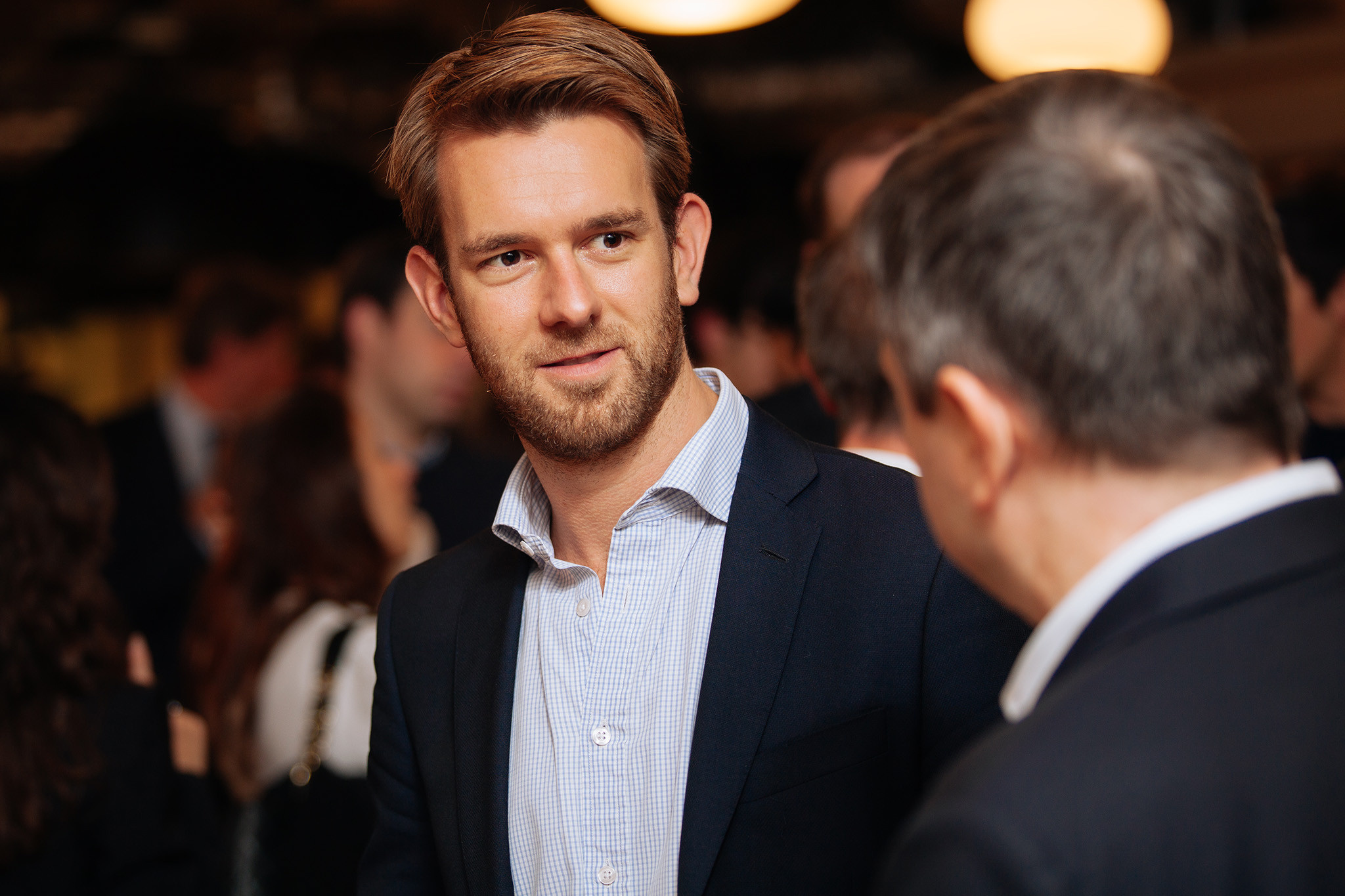A man wearing a blue shirt and a black jacket.