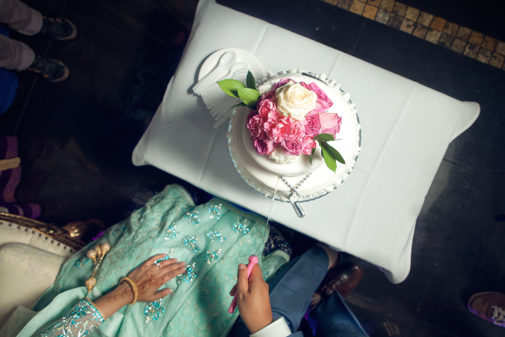 A woman in a green dress is holding a pink rose.