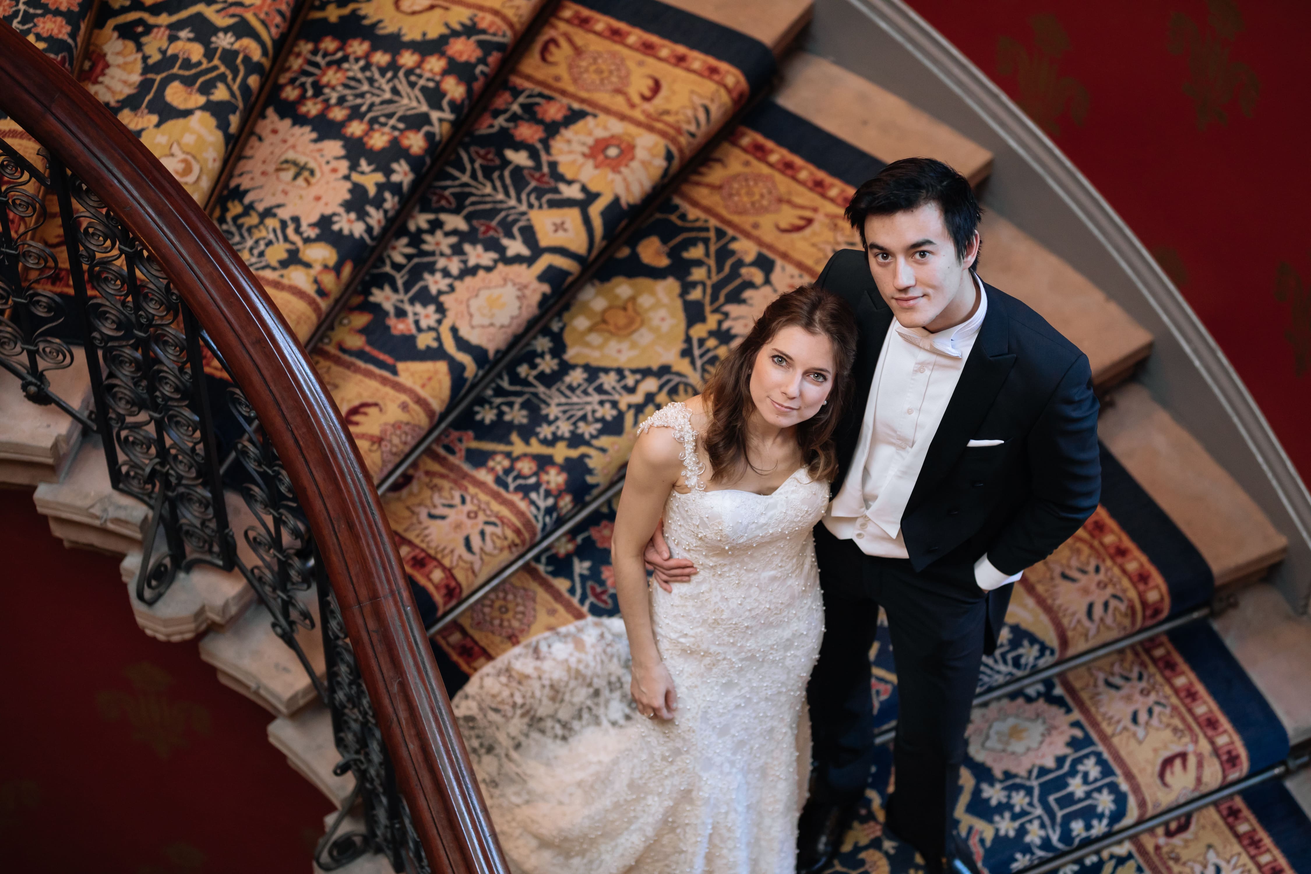 A bride and groom pose for a picture on a staircase.
