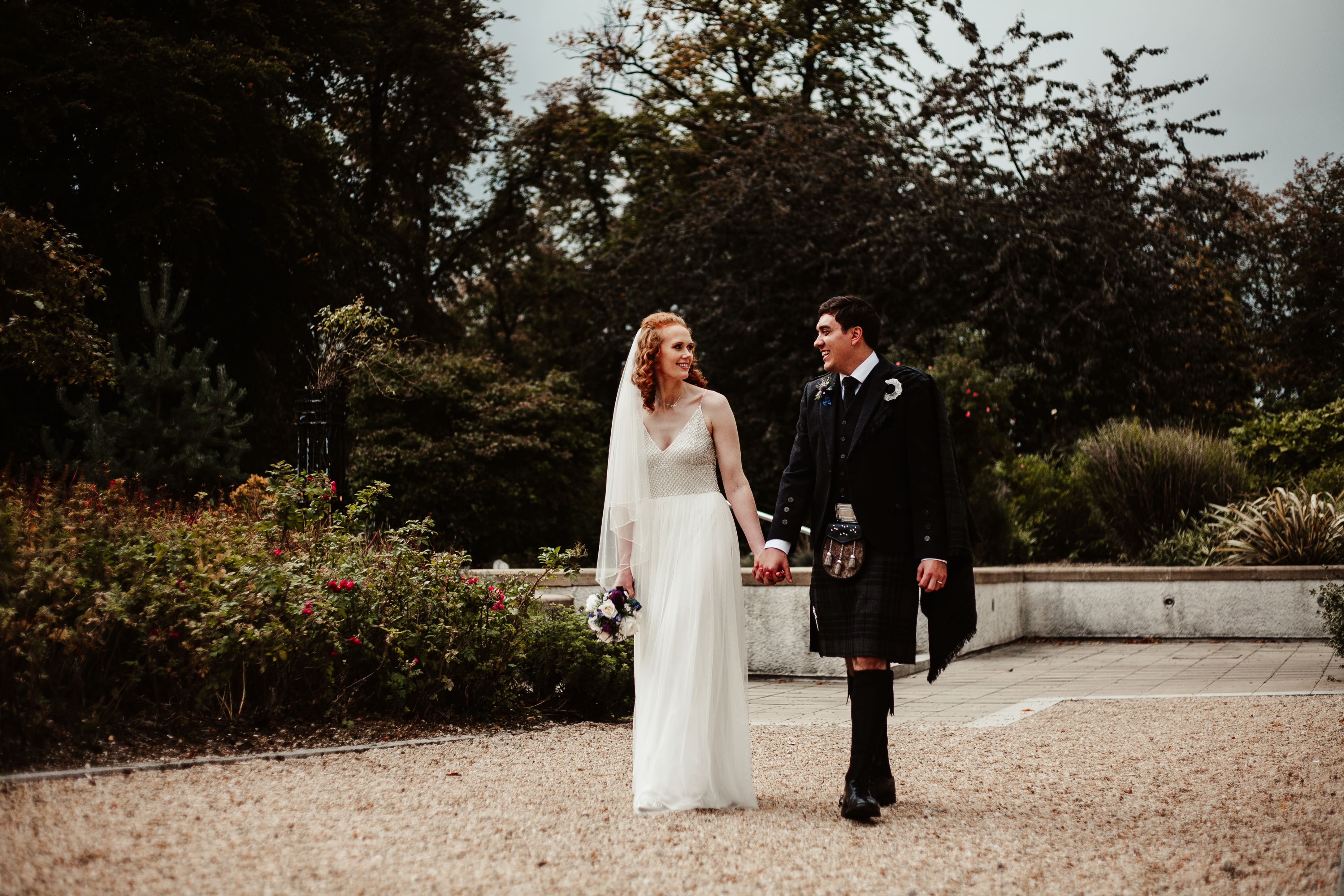 A bride and groom walking down a path.