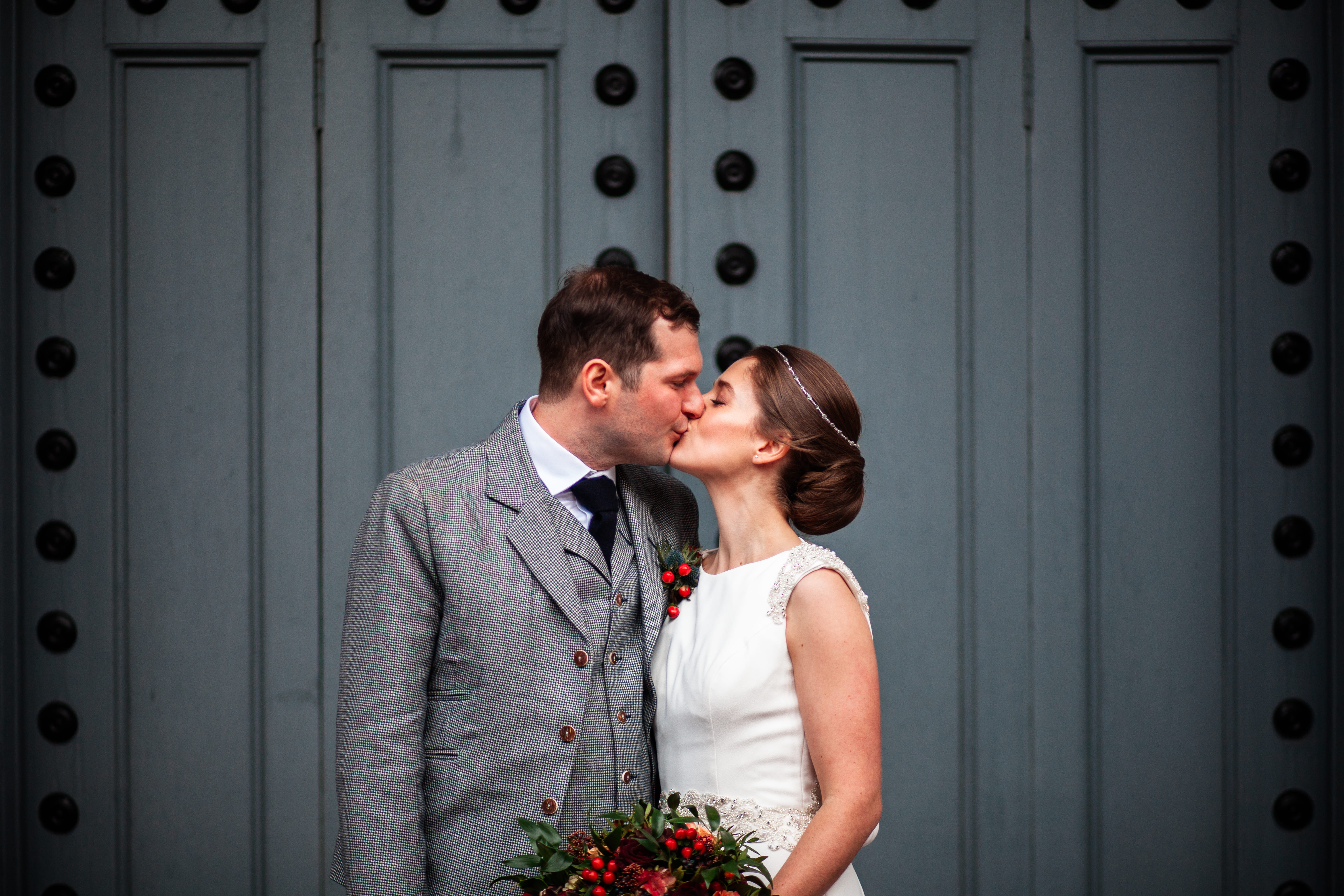 A bride and groom kissing in front of a door.