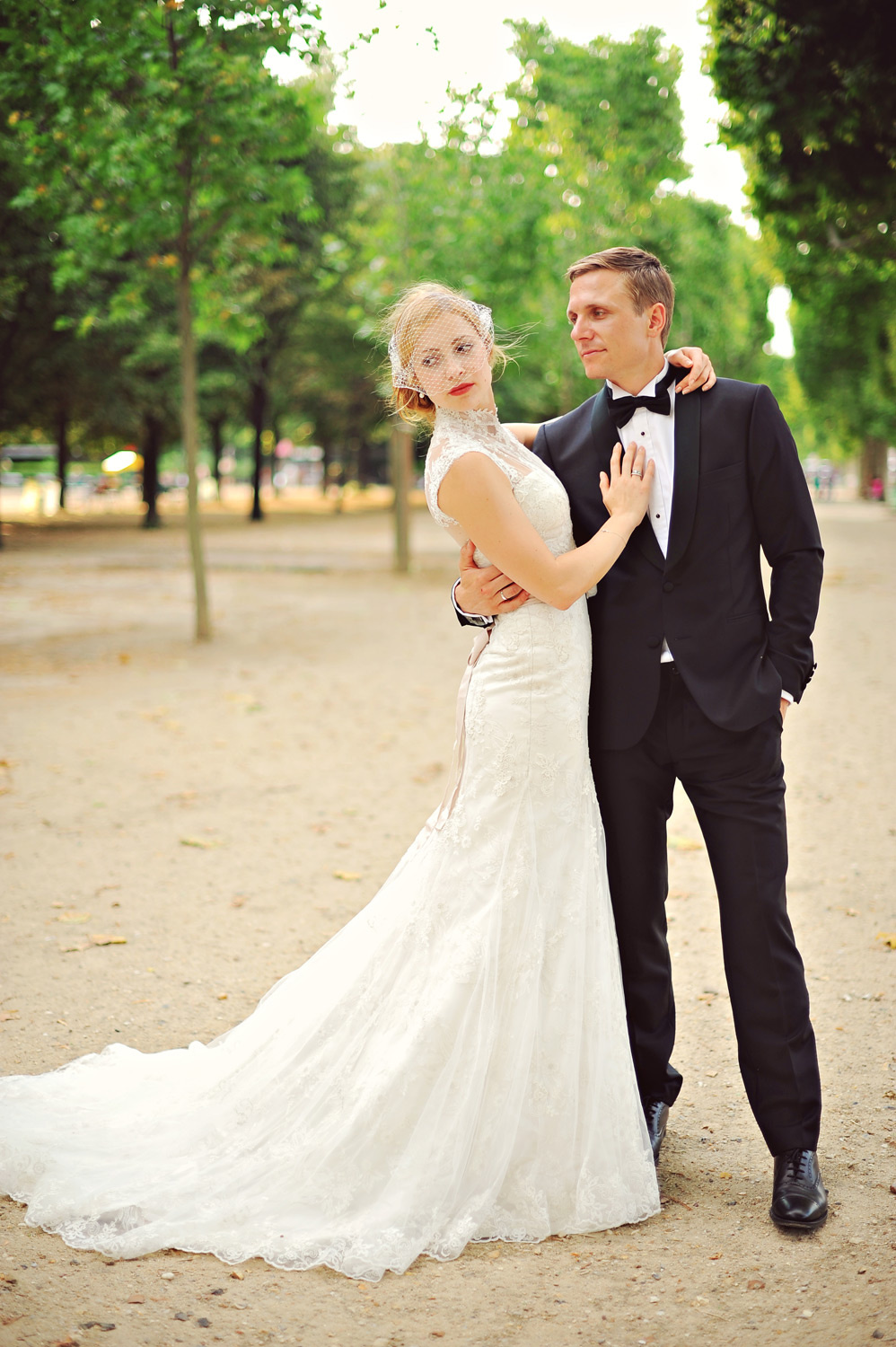 A bride and groom pose for a picture in a park.