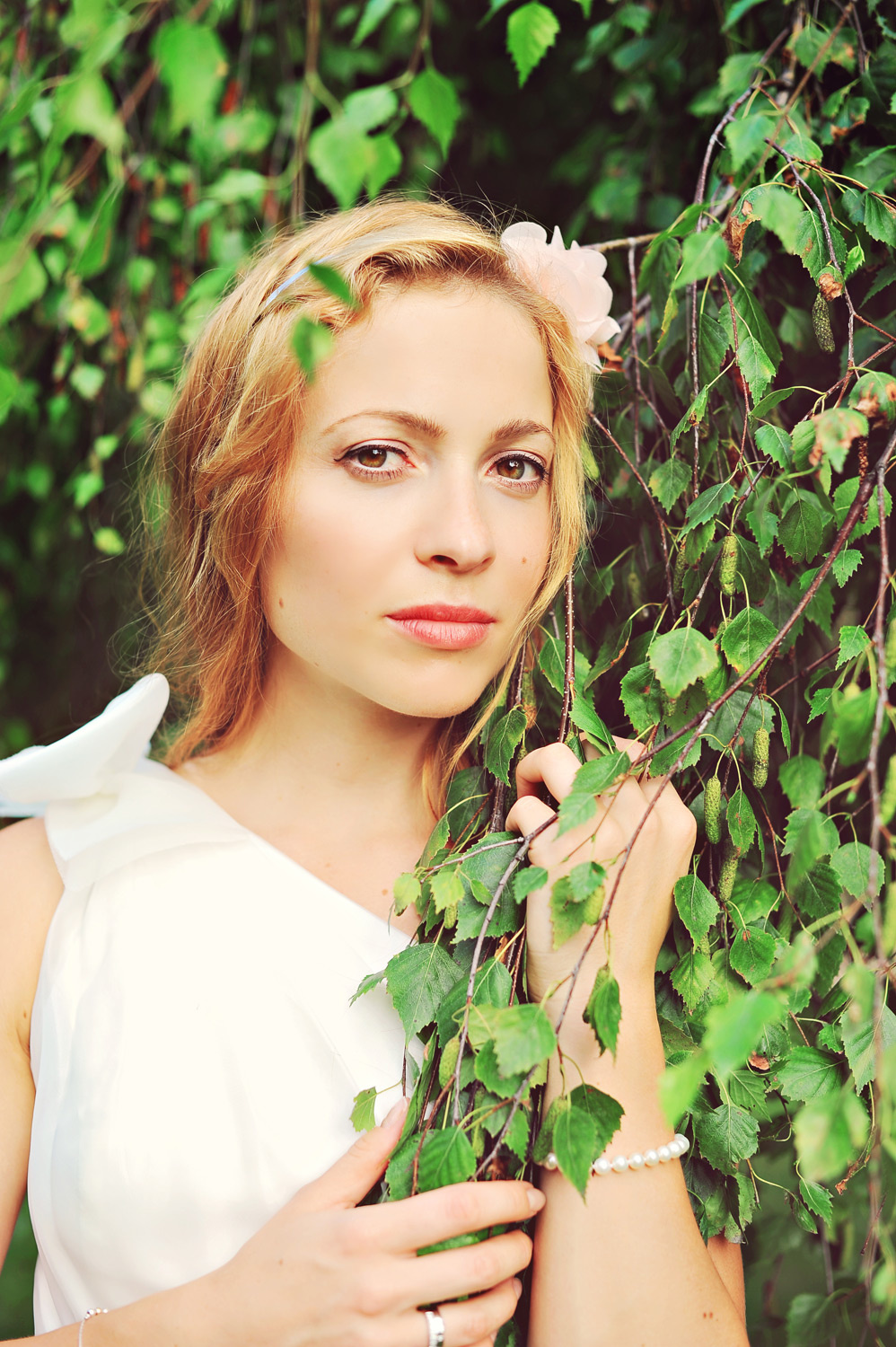 A woman wearing a white dress and holding a leaf.