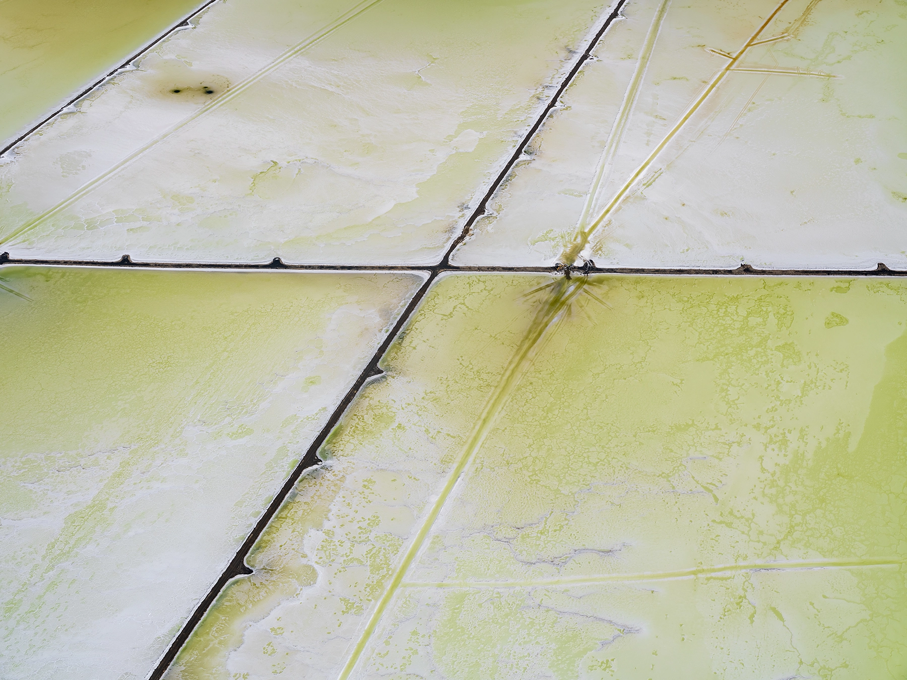 Aerial view of Compass Minerals solar evaporation ponds at the Great Salt Lake, showing geometric patterns of colorful mineral extraction ponds, levees, and industrial infrastructure impacting the lake's ecology.