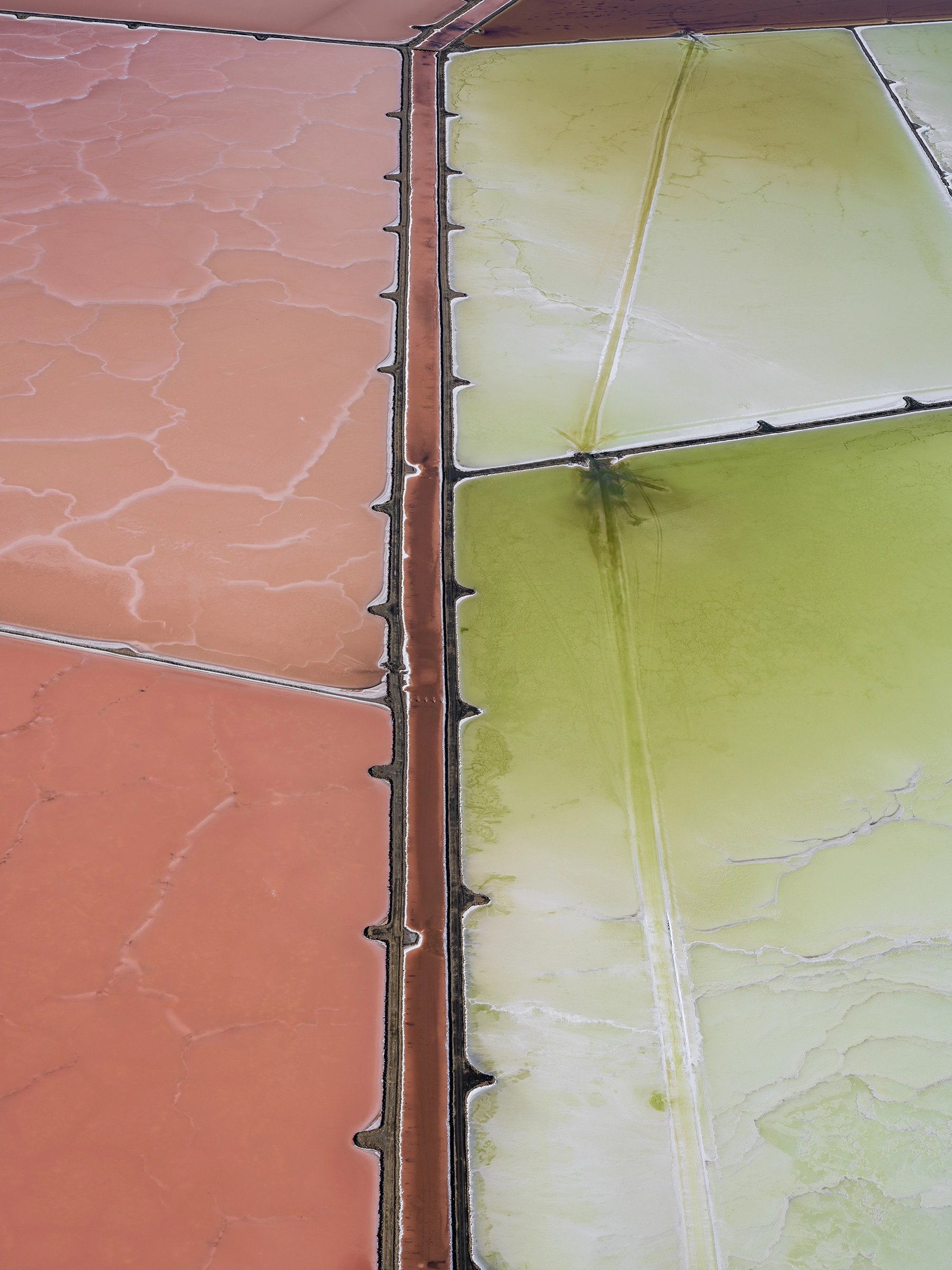 Aerial view of Compass Minerals solar evaporation ponds at the Great Salt Lake, showing geometric patterns of colorful mineral extraction ponds, levees, and industrial infrastructure impacting the lake's ecology.