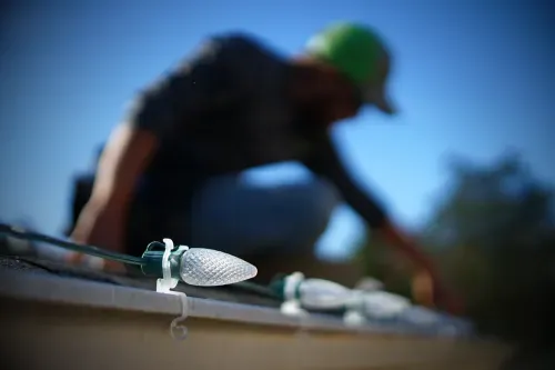 An image of a Crosscut employee installing Christmas lights on a roof.