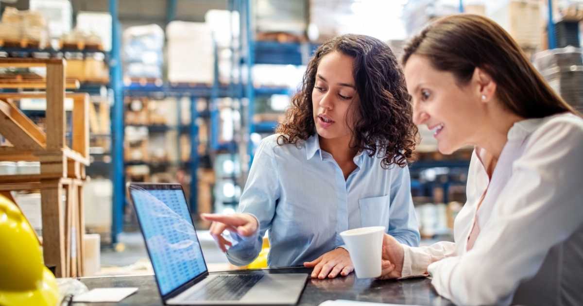 warehouse workers reviewing inventory on a laptop