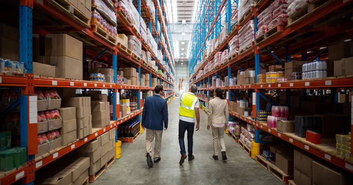 people walking down a warehouse aisle
