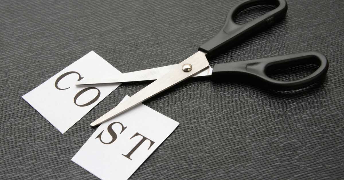 A pair o scissors that cut a piece of paper in half with cost written on it.