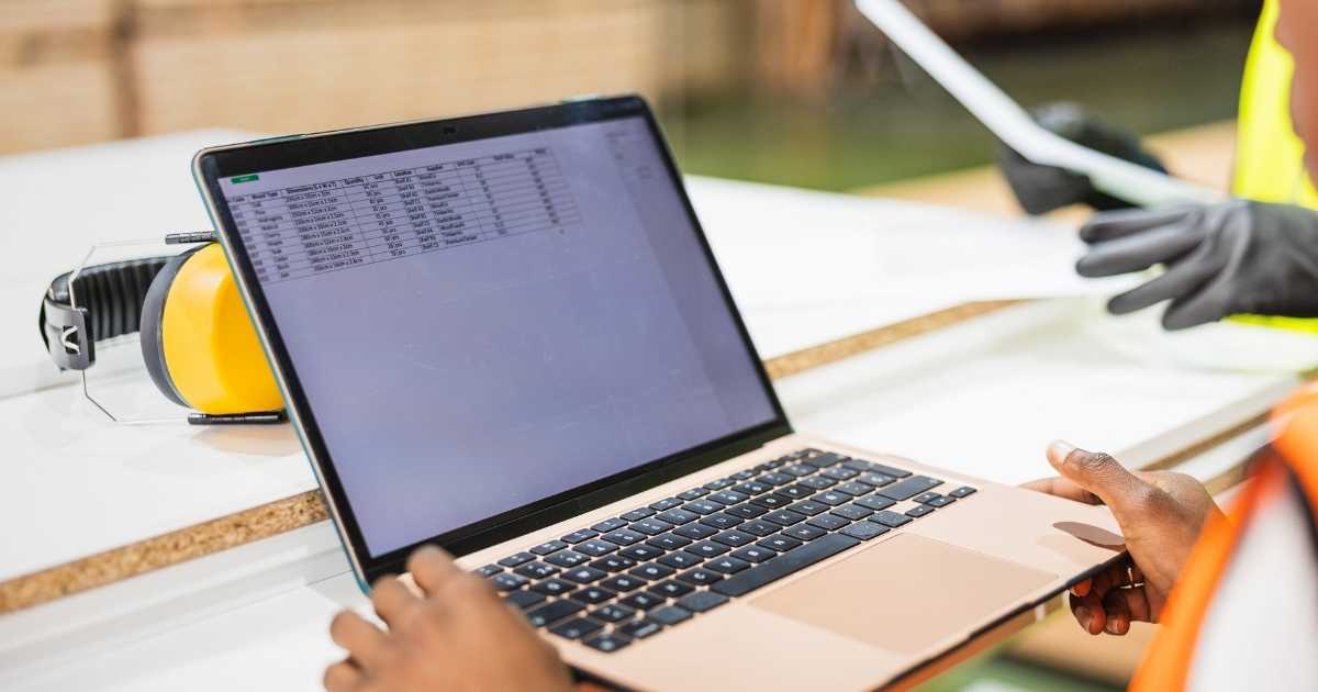 A warehouse worker tracking inventory on a laptop.