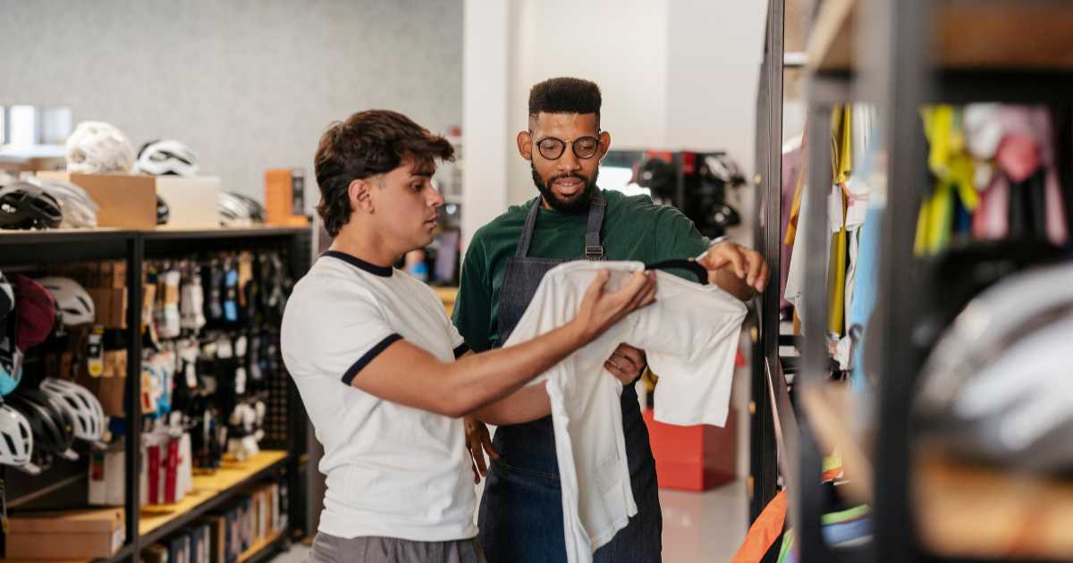 A picture of a store associate helping a customer with a tshirt selection.
