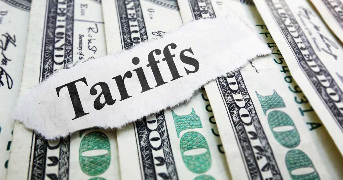 A picture of US money with a piece of paper with Tariffs printed on it.