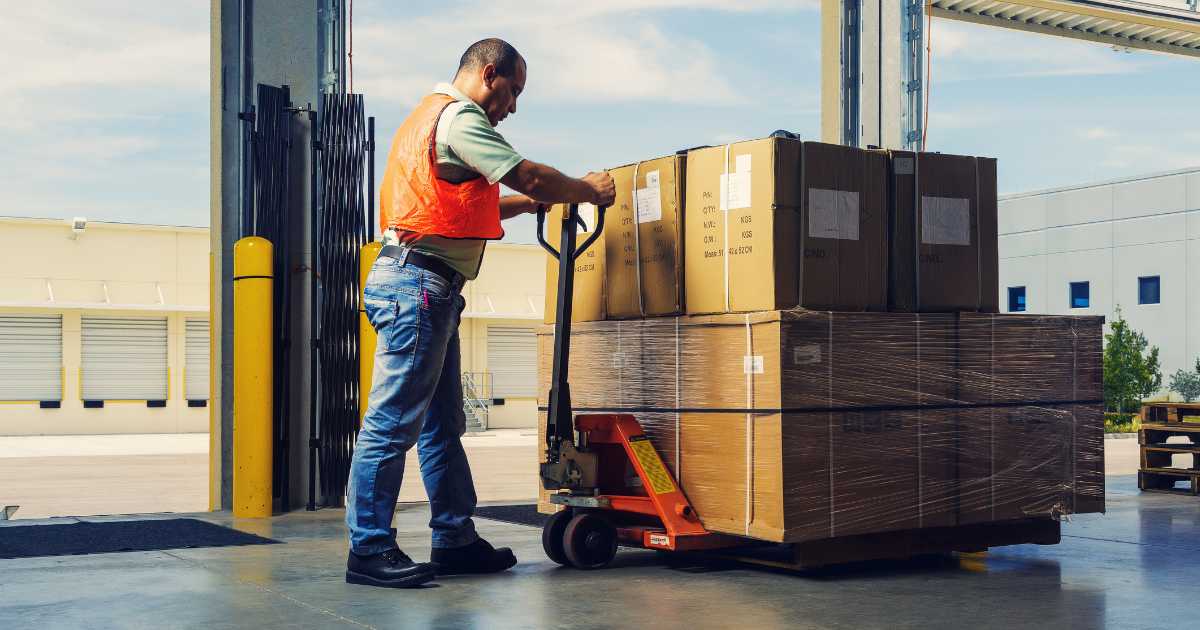 A warehouse worker on a loading dock with a palletized shipment.