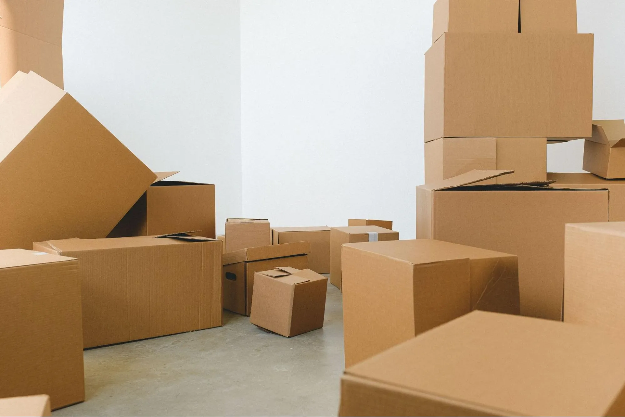 Boxes of various sizes are piled on top of each other in an otherwise empty room.