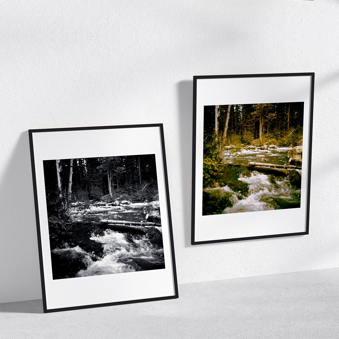 Side-by-side framed prints of “Grand Teton Rapids, Wyoming” shown in a clean wall mockup: the left print is black-and-white and the right is in color, both capturing rushing river rapids cutting through a pine forest with fallen logs across the water.
