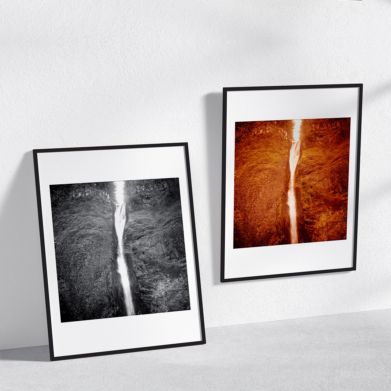 Wall mockup showing two framed, white-matted prints of Horsetail Falls: a black-and-white version leaning on the left and a warm, amber-toned color version hanging on the right, both featuring a tall waterfall cutting through steep, textured cliff walls.