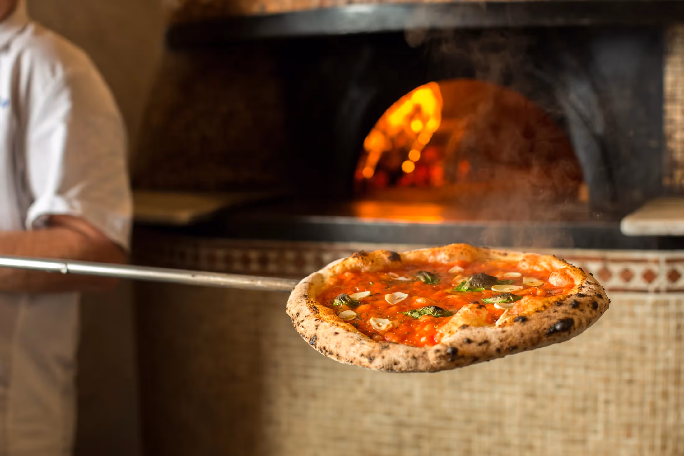 Chef at Il Pizzaiolo taking a pizza out of the wood fire oven