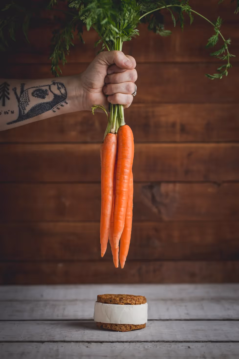 Hand holding carrots above a Leona's Ice Cream Sandwich