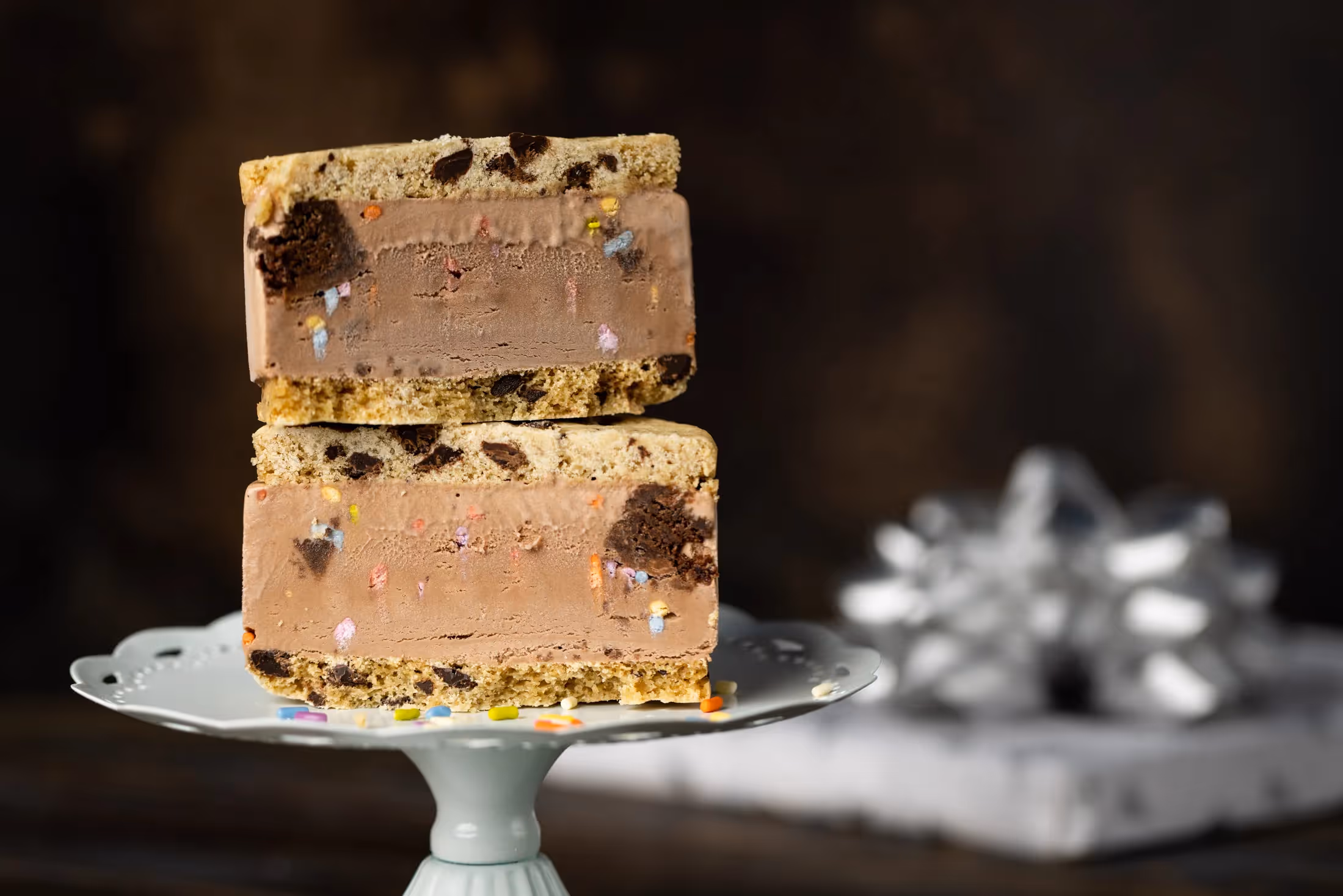 Leona's Ice Cream Sandwiches stacked on a cake stand with a present in the background