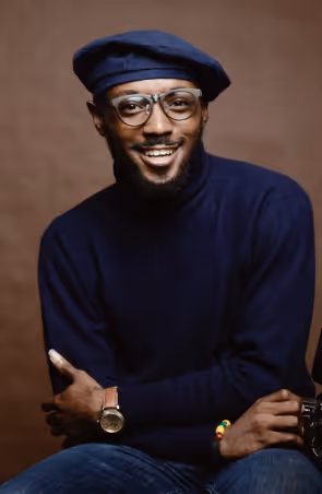 A man with a hat and glasses sitting on a chair.
