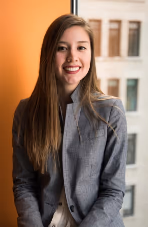 A woman standing in front of a window smiling.