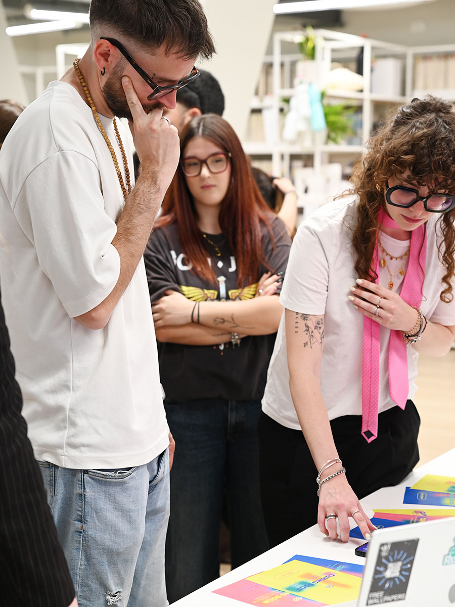 Studenti del corso di Progettazione Multimediale del SID osservano e discutono materiali grafici e prototipi durante la mostra finale con Lorenzo Grosso