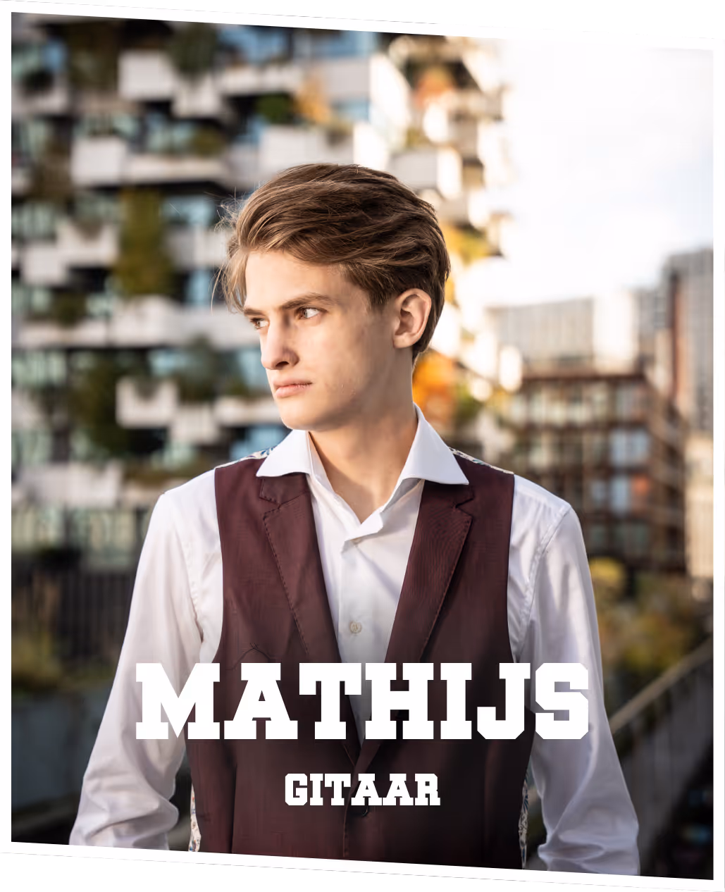 Mathijs (gitaar) Mathijs, gekleed in een paars pak, zittend met een elektrische gitaar op schoot voor een klassieke auto.