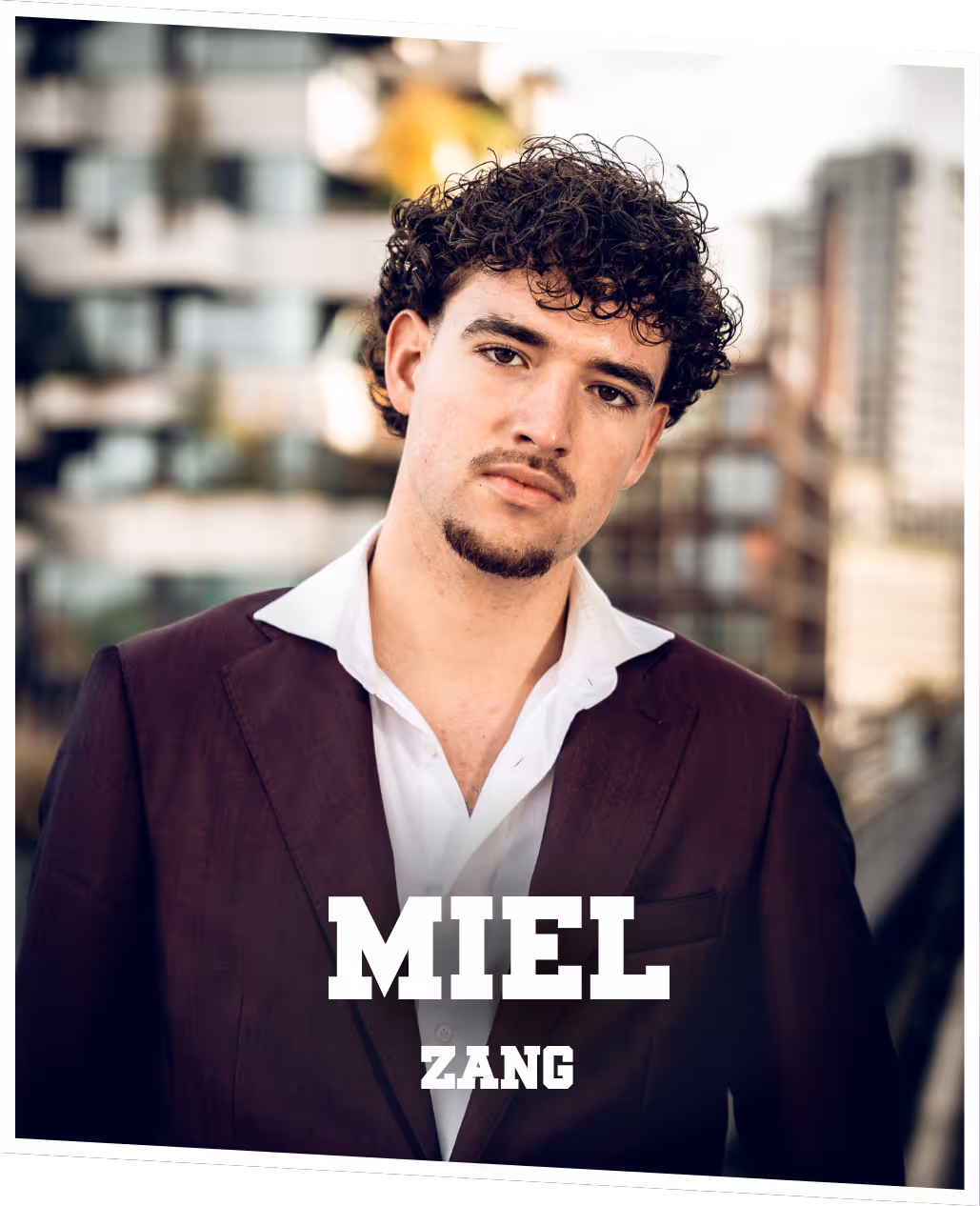 Miel (zang) Close-up van Miel die met zijn armen op een open autodeur rust, gekleed in een paars pak.