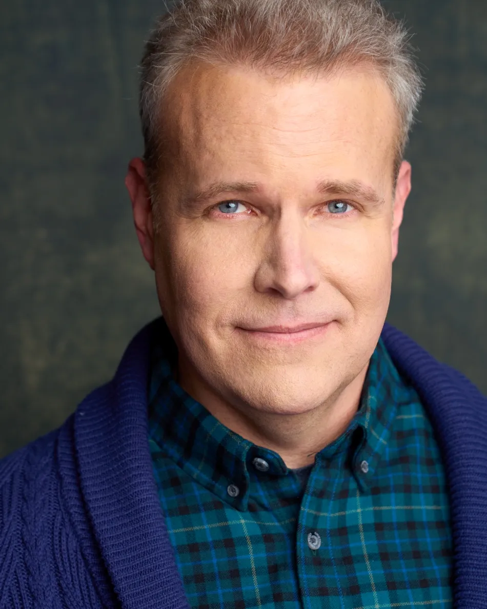 Atlanta theatrical actor headshot — middle-aged male actor with friendly smile, plaid shirt and cardigan, warm Hallmark dad type look.