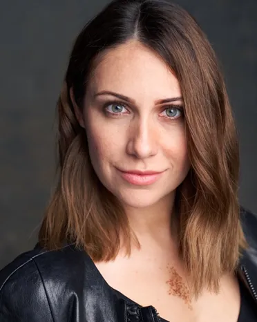 Virginia D.C. actor headshot — female actor with confident expression, blue eyes, leather jacket against neutral studio background, theatrical style.