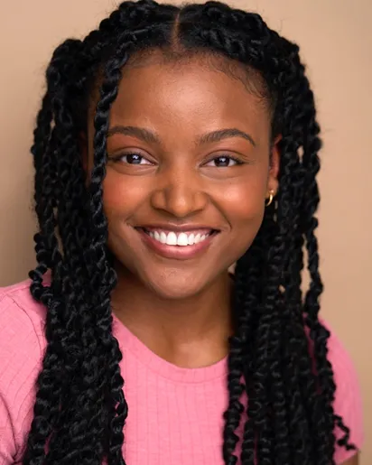 Virginia D.C. commercial actor headshot — young Black female actor with long braids, bright smile in pink top against beige background, approachable commercial style.