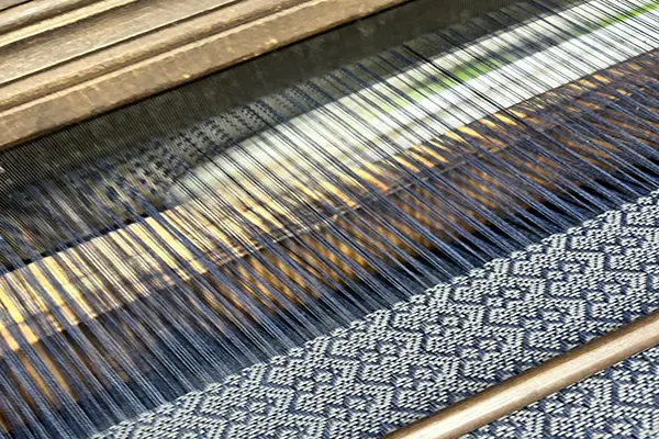 warp threads and woven textile on a traditional shuttle loom