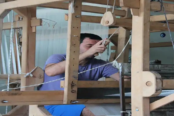 A weaver working inside the frame of a traditional shuttle loom in Türkiye