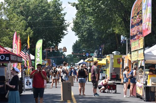 People walking in the vendor-lined streets of Downtown Hanover, PA at Snack Town Street Fair