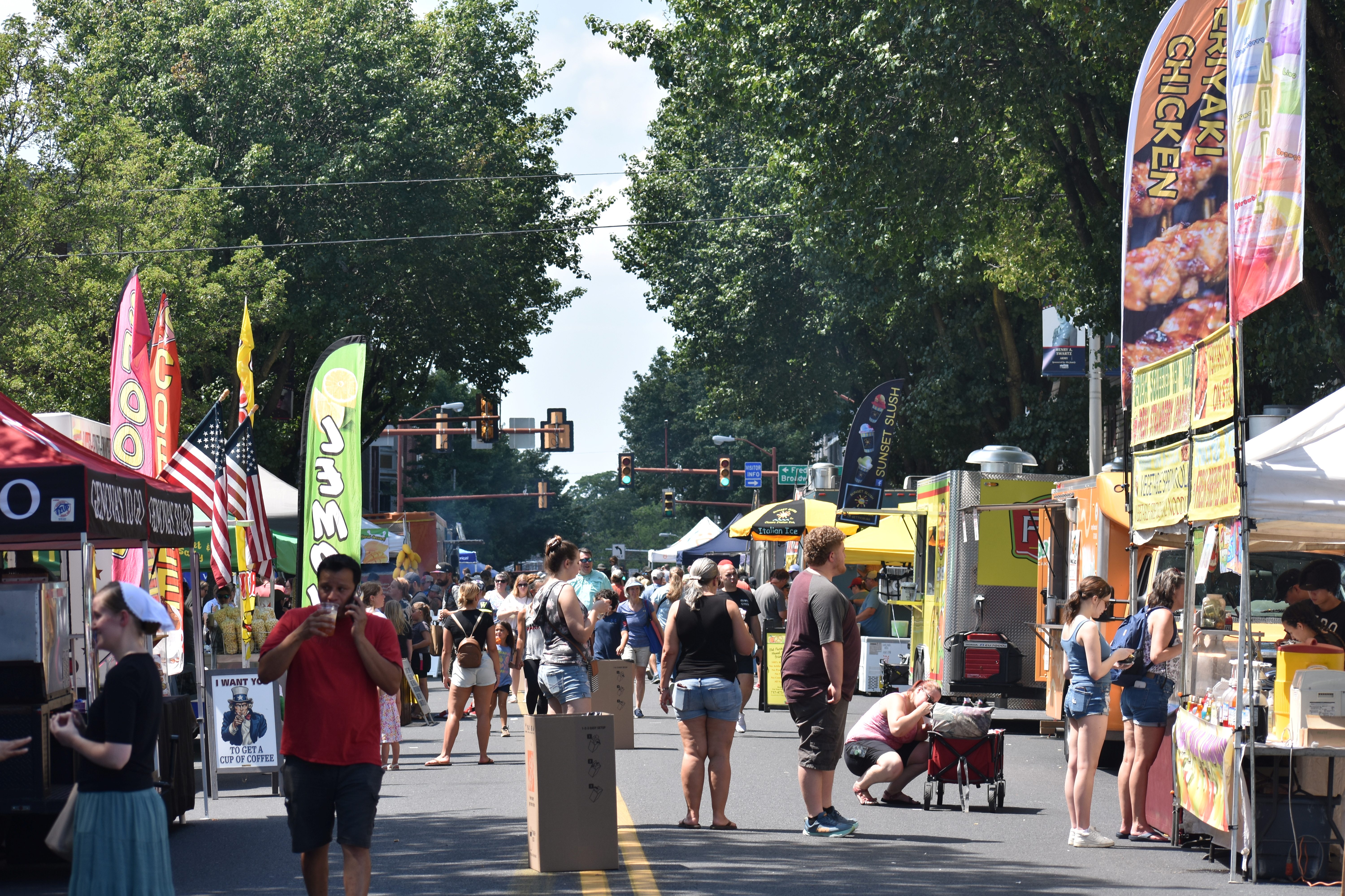 People walking in the vendor-lined streets of Downtown Hanover, PA at Snack Town Street Fair