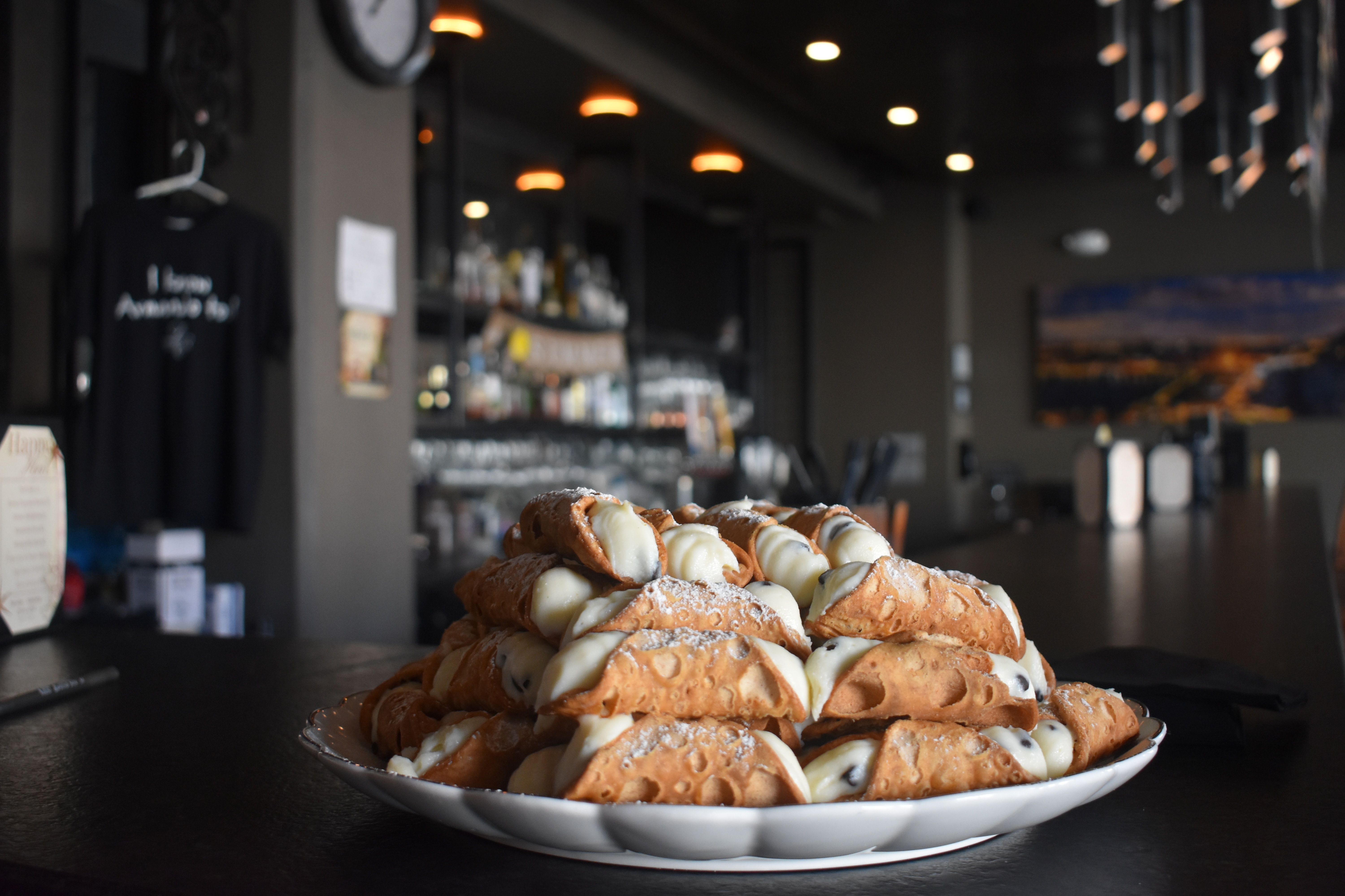 A plate of cannolis sit atop a stone bar top and room with a modern, high-end look