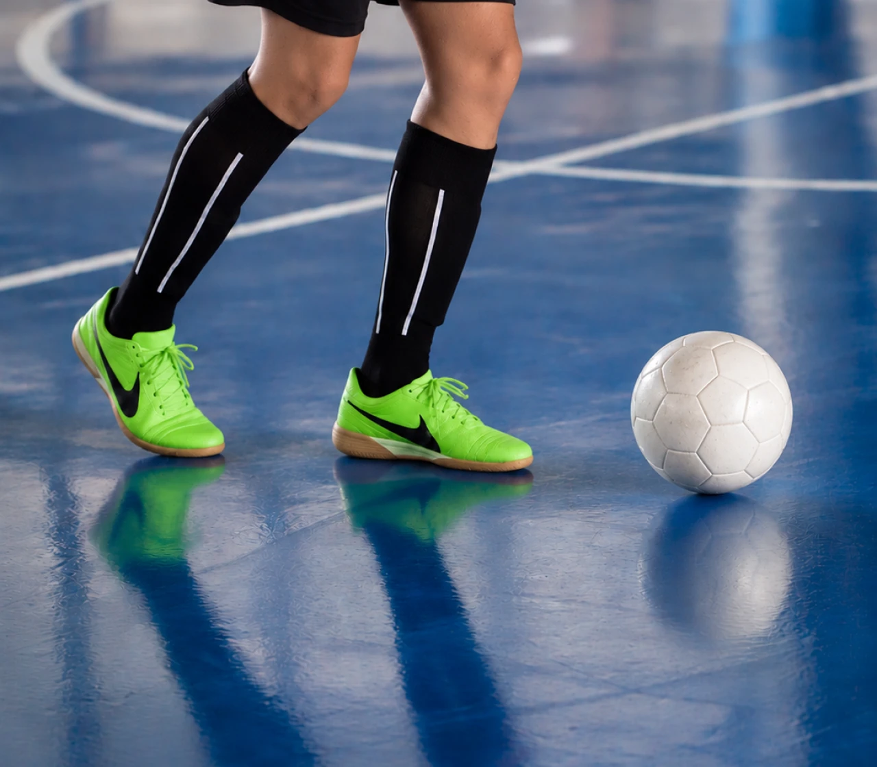 Young futsal player dribbling a ball on a blue indoor court