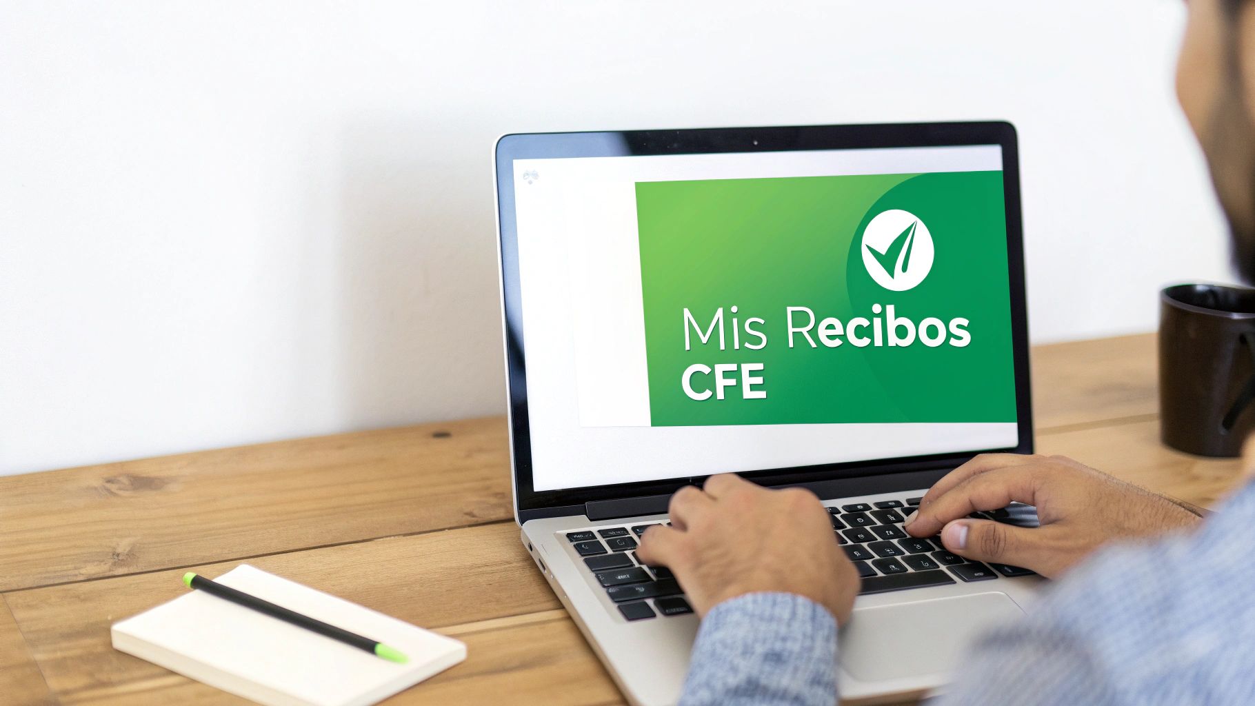 Persona usando una laptop para consultar sus recibos de luz CFE en una mesa de madera, con un cuaderno.