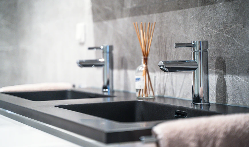Moderne wastafel met twee kranen in een strak afgewerkte badkamer.