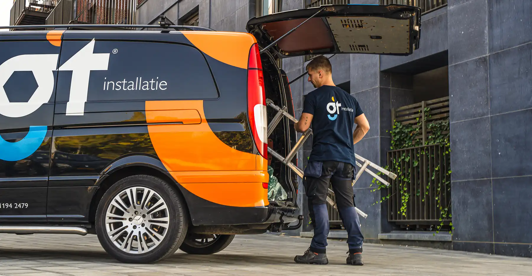 Monteur van GT Installatie pakt een ladder uit de bedrijfsbus bij aankomst op locatie.