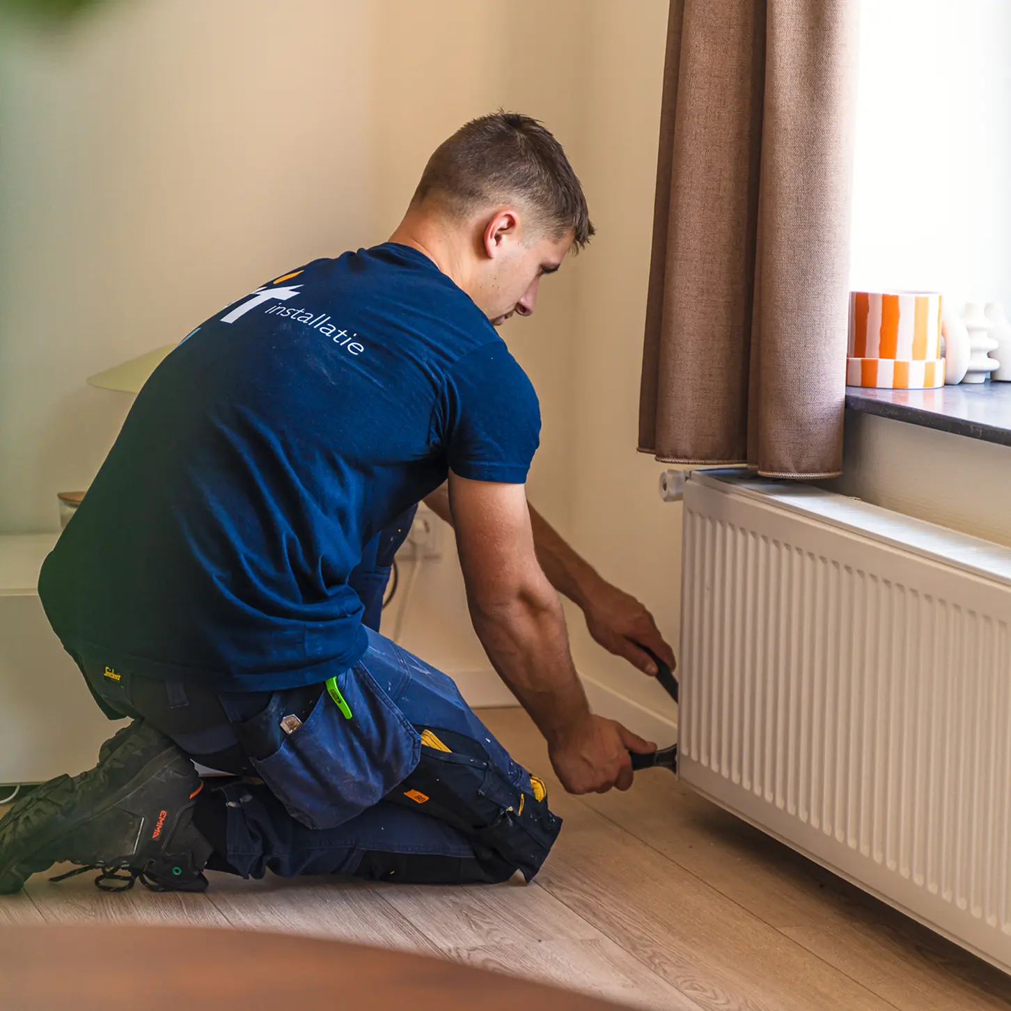 Installatiemonteur plaatst radiator in woning voor efficiënte verwarming en comfortabel binnenklimaat.