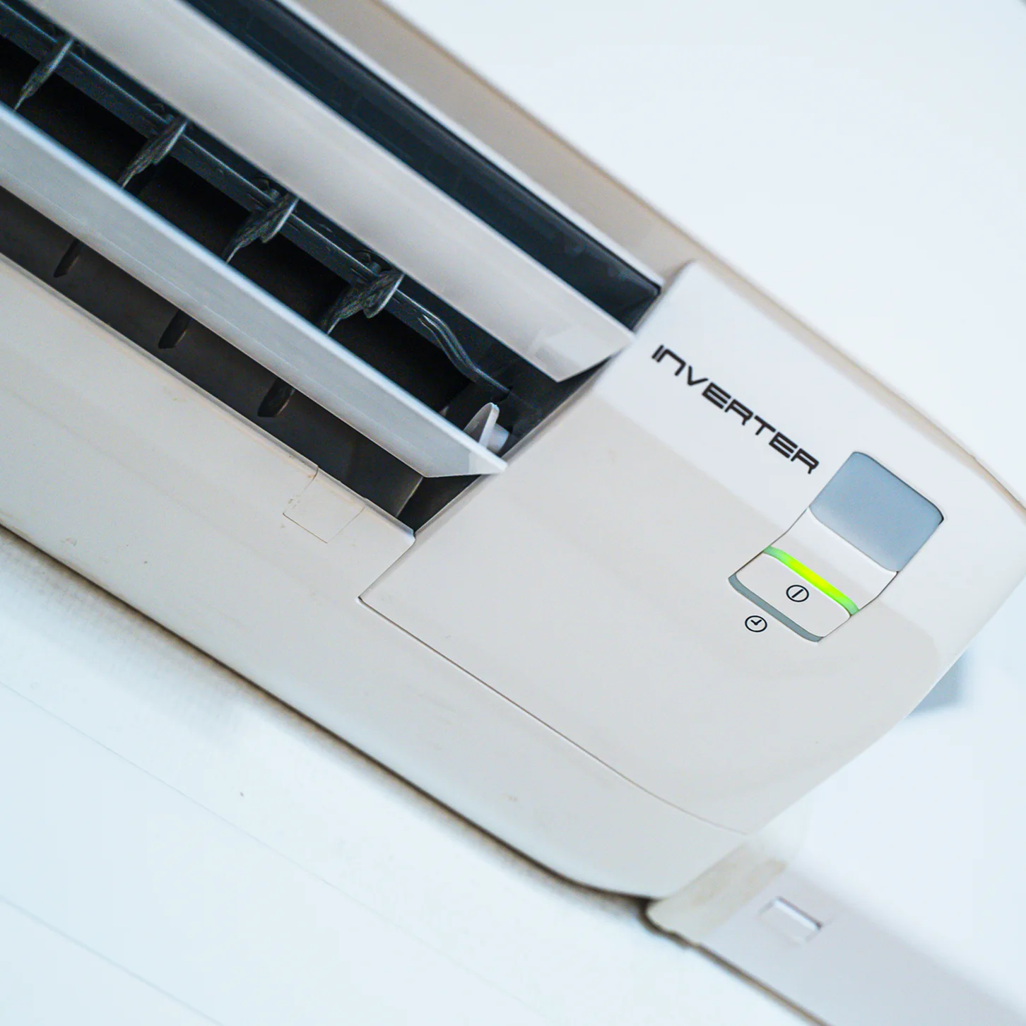 Airconditioningunit met invertertechnologie aan de muur, detail van ventilatieroosters en bedieningspaneel.