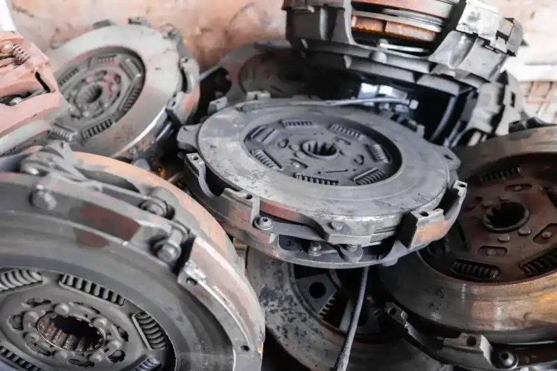 Stack of worn heavy-duty clutch assemblies removed from commercial vehicles, showing signs of rust, friction wear, and heat damage.