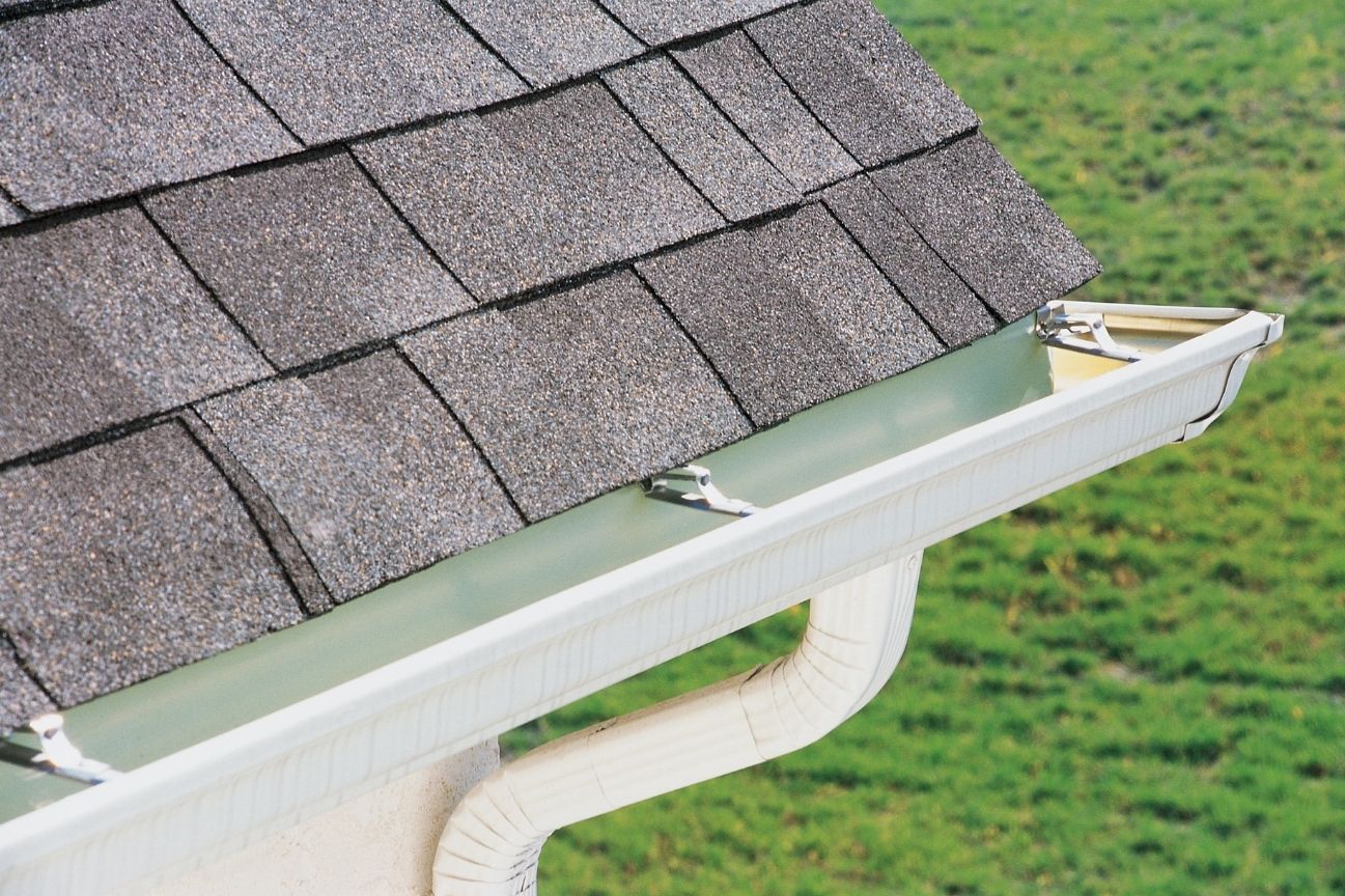 White aluminum gutter system with hidden hangers on asphalt shingle roof edge