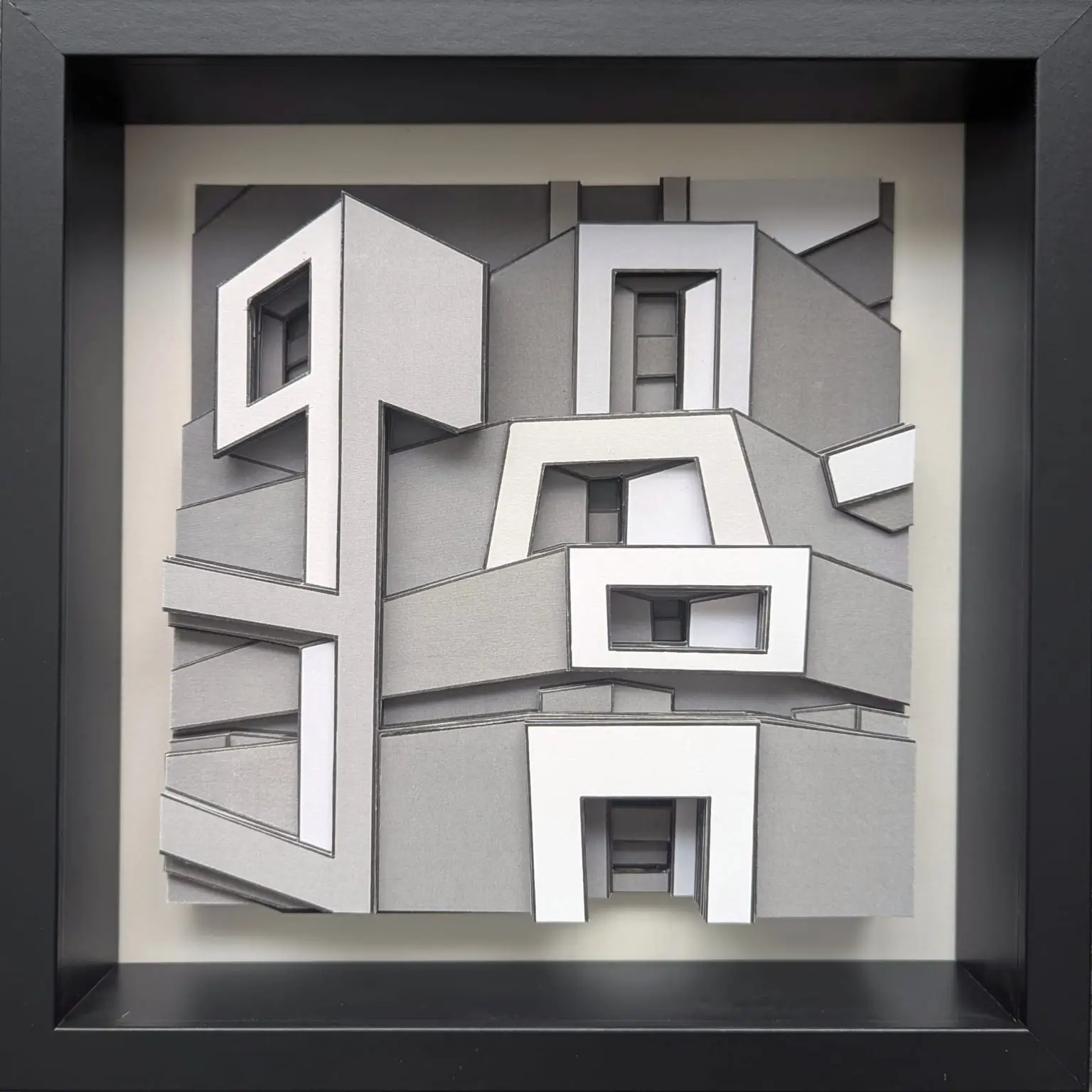 Collage monochrome en nuances de gris et blanc, volumes architecturaux imbriqués créant un relief géométrique puissant.