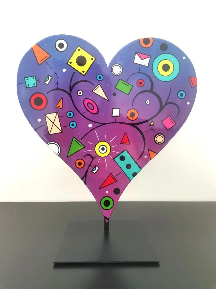 Cœur en bois bleu et rose, formes géométriques ludiques, cercles et triangles colorés, monté sur socle noir.